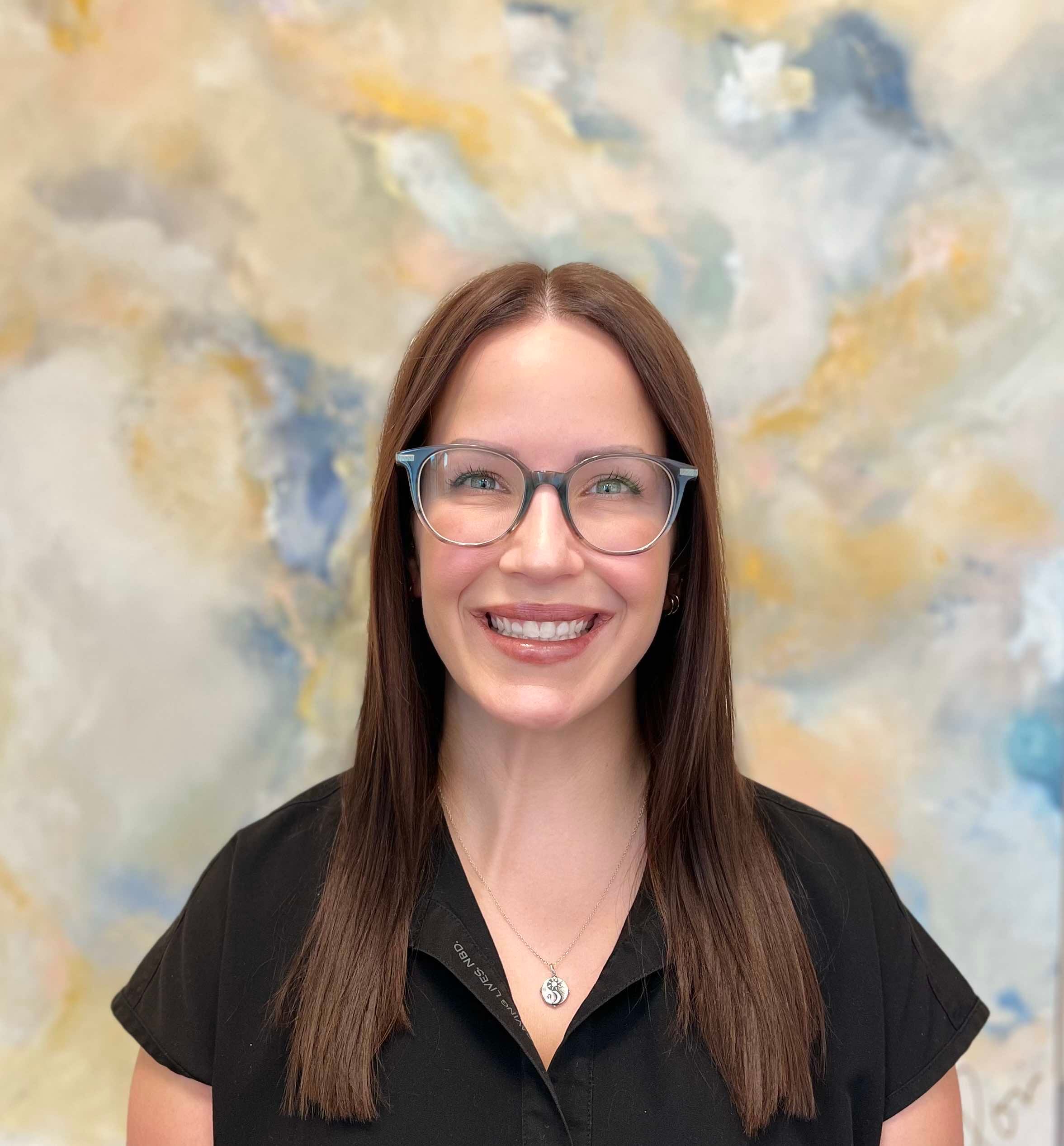 About - Edward Love MD Karrie Wright, skin care specialist at Edward Love MD, smiling in a black top against a soft, abstract background, representing a welcoming atmosphere for patients seeking aesthetic and reconstructive surgery.